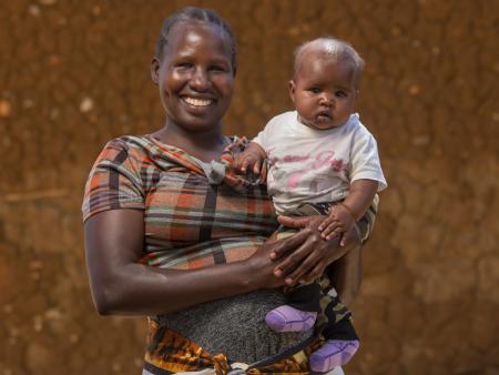 Smiling woman holding up her baby